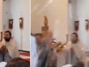 Un preot binecuvântează enoriaşii cu furtunul, în biserică