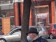 Imagine virală! Un bătrân îmbărcat elegant, ține un buchet de flori în mână în așteptarea femeii iubite